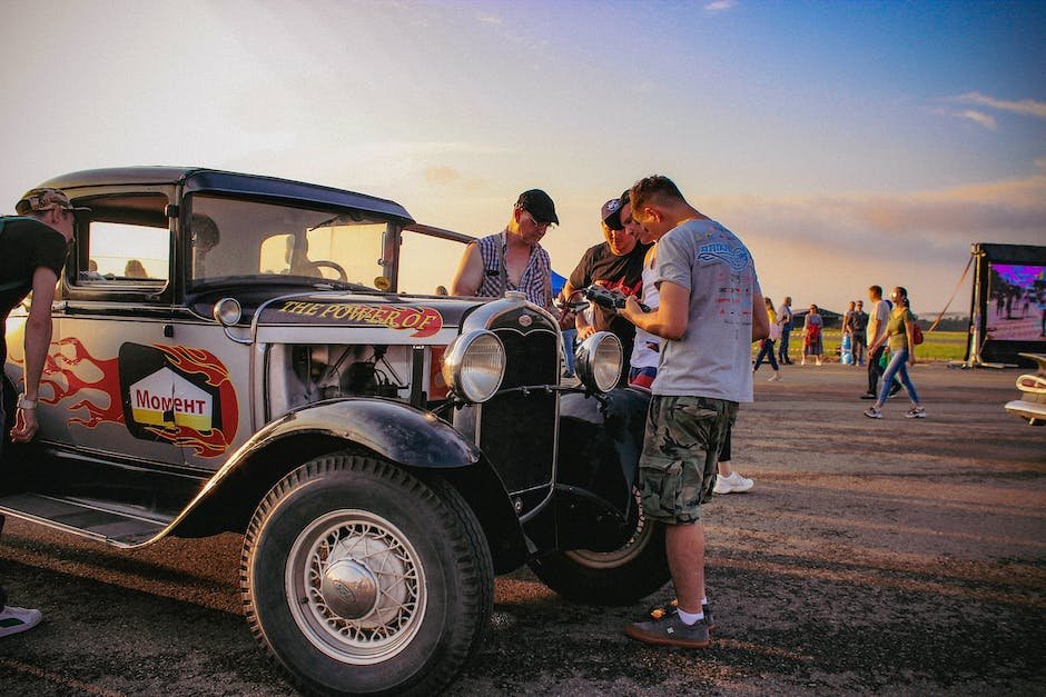 A group of classic car enthusiasts gathered around a vintage vehicle at a car show