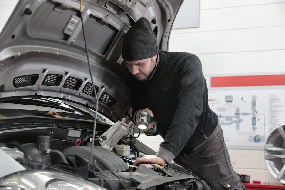 A mechanic inspecting a car engine with a wrench in hand.